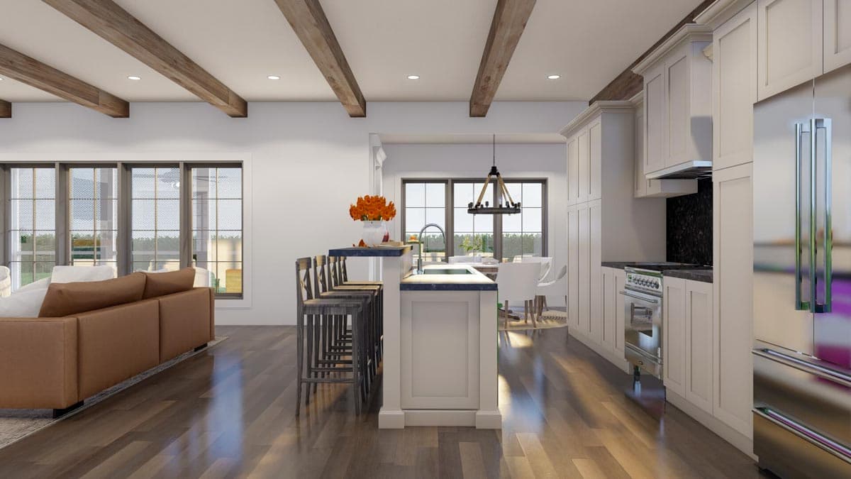 Interior view of a kitchen and living area with exposed wood beams, a large island with bar stools, and a sectional sofa.