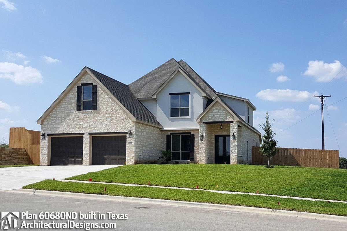 House plan exterior featuring stone facade, two-story design, gabled dormer, and attached three-car garage.