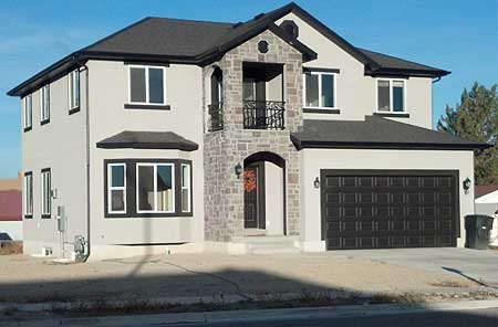 Two-story house plan exterior with stone-clad entry, bay window, and attached two-car garage.