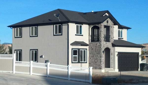 Two-story house plan exterior with stone facade, second-story balcony, arched entry, and attached garage.