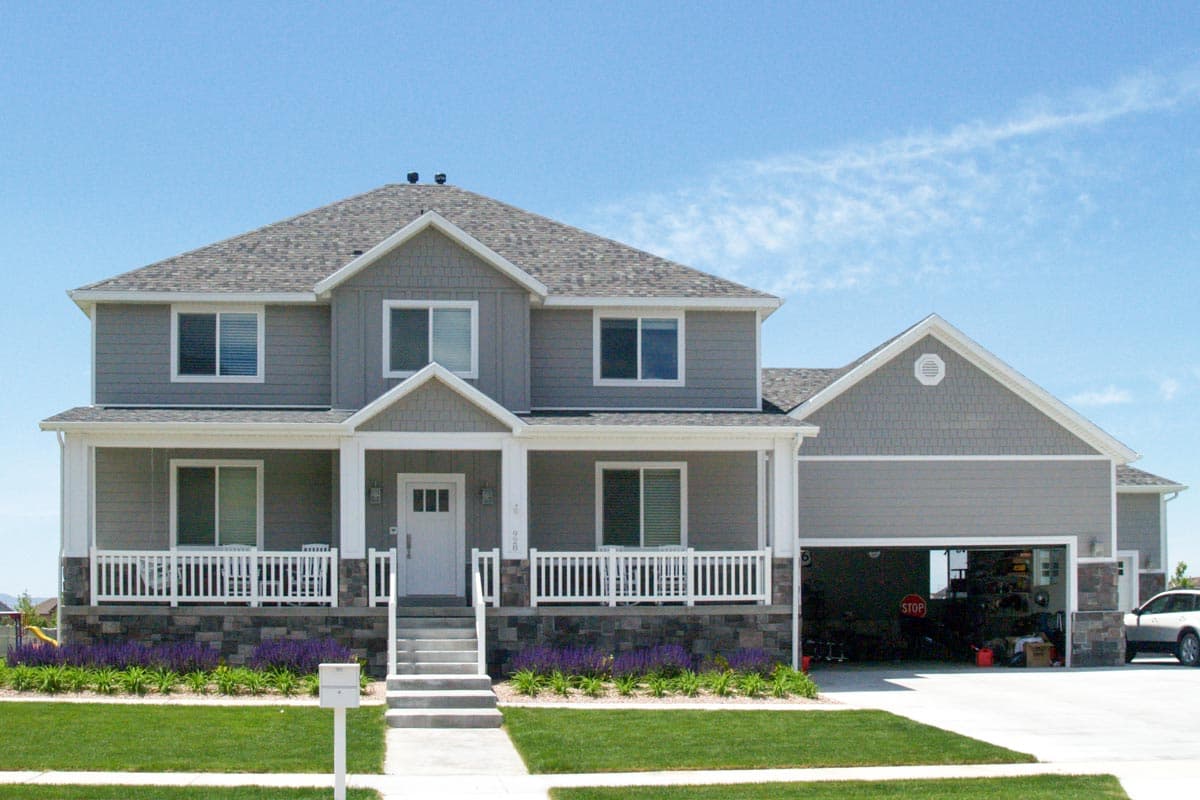 House plan exterior: two-story home with a covered front porch, multi-level gables, and attached side-entry garage.