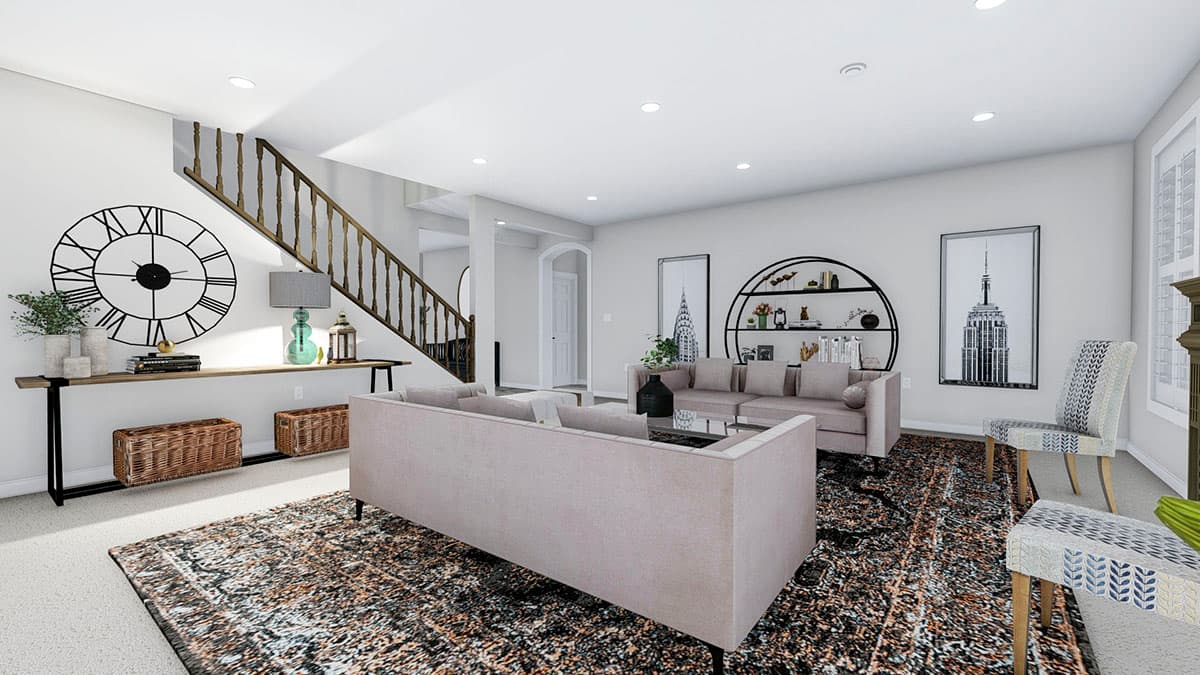 Great room with open layout, sectional sofa, staircase with wooden balusters, and large wall clock.