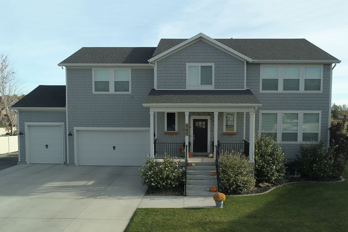 Two-story house plan exterior with shingle siding, a covered front porch, and a two-car attached garage.