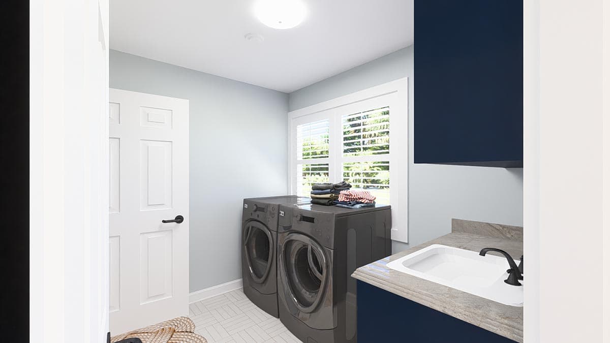Laundry room with gray washer and dryer, white door, navy cabinets, and a sink with a black faucet.