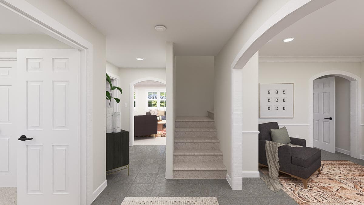 Interior view of a home foyer with arched doorways, stairs to an upper level, and a seating area with a chaise lounge.