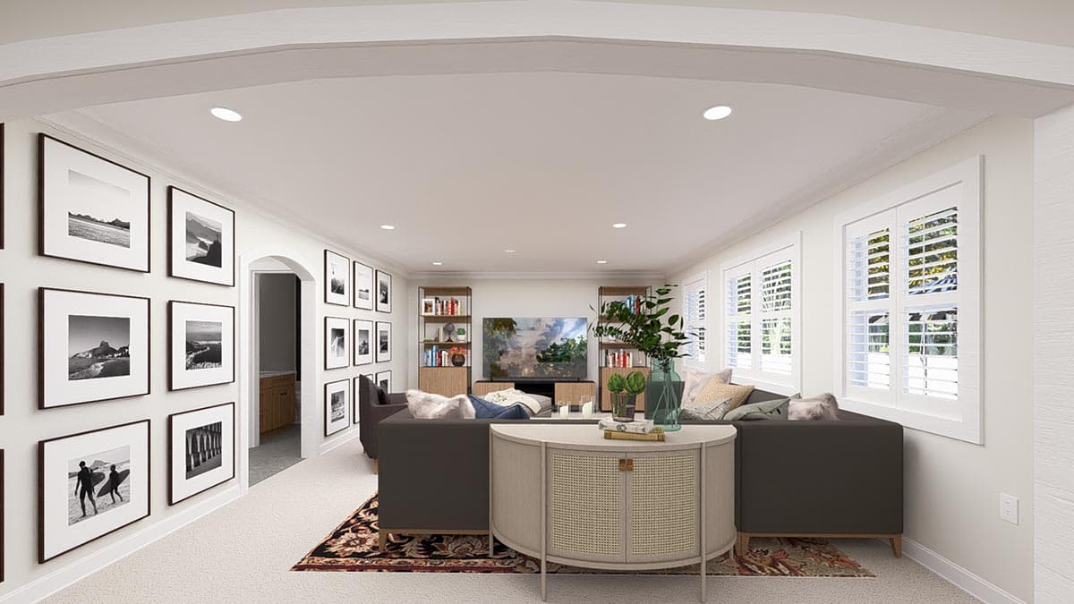 Living room with arched entry, gallery walls, television, bookshelves, sofas, and plantation shutters.