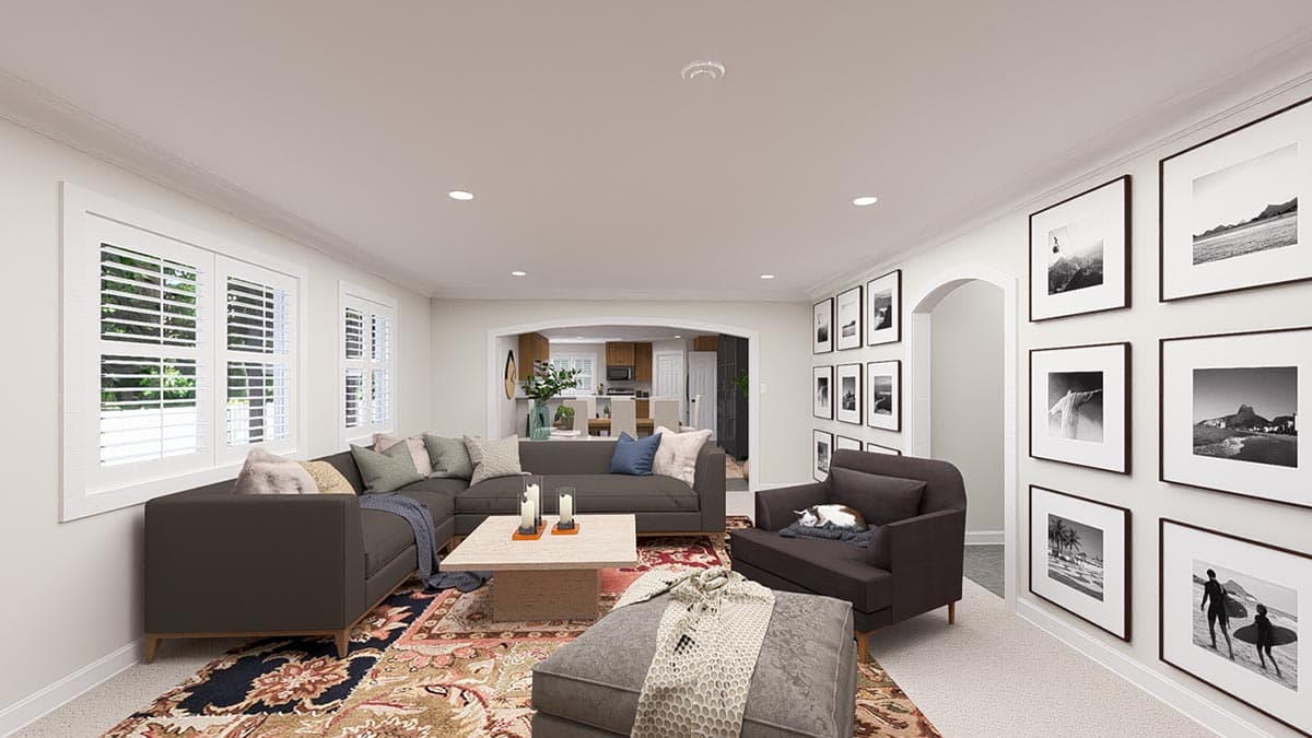 Living room with sectional sofa, armchair, ottoman, patterned rug, and framed artwork. Archway reveals kitchen.
