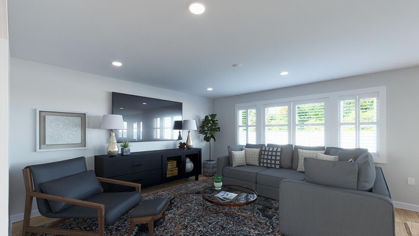 Living room with sectional sofa, coffee table, media console, armchair, and large windows with plantation shutters.