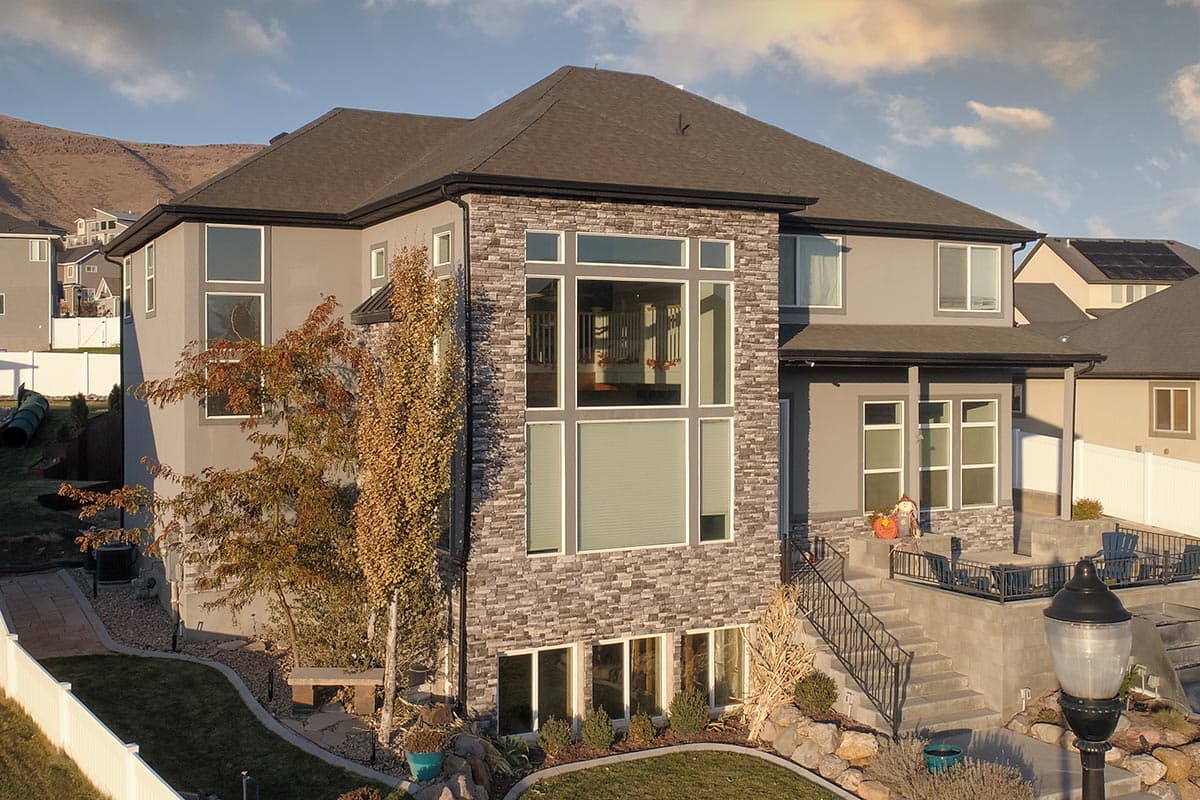 Modern two-story house plan exterior with stone facade, large windows, gabled roof, and covered porch.