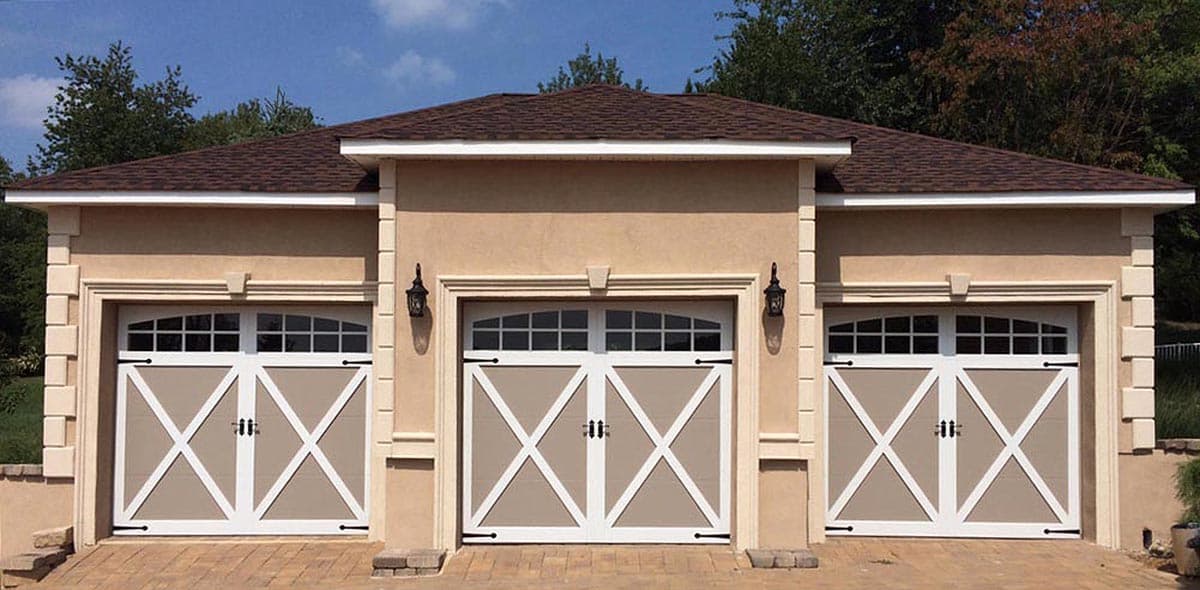 House plan exterior of a three-car garage with arched, multi-pane windows above X-design doors and decorative stone trim.