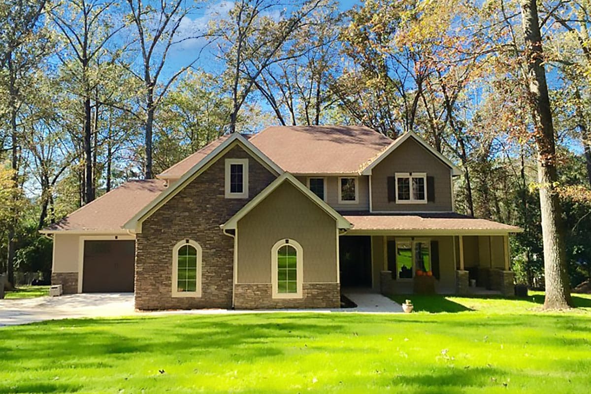 Two-story house plan exterior with stone accents, multiple gables, a covered front porch, and an attached side-entry garage.
