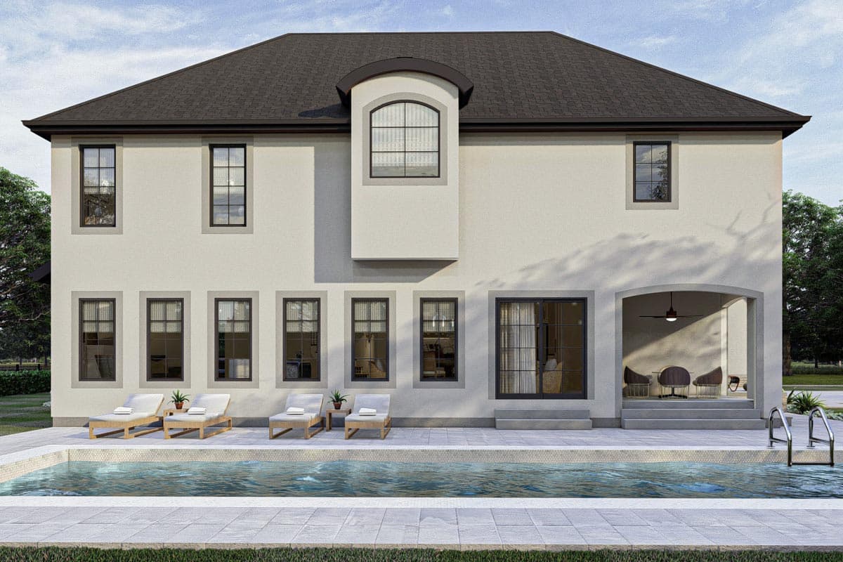 House plan exterior: Two-story stucco home with multiple gabled dormers, arched window detail, and covered patio with seating.