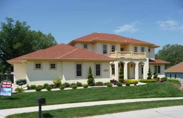 House plan exterior: two-story house with arched entryway, second-story balcony, and red tile roof.