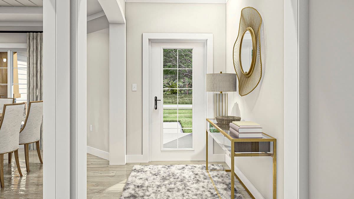 Interior view of a hallway with a glass-paned door, a console table with books, and a decorative mirror.