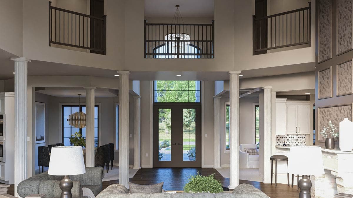 Interior view of a house with a two-story foyer, grand staircase, double front doors, and open living spaces.