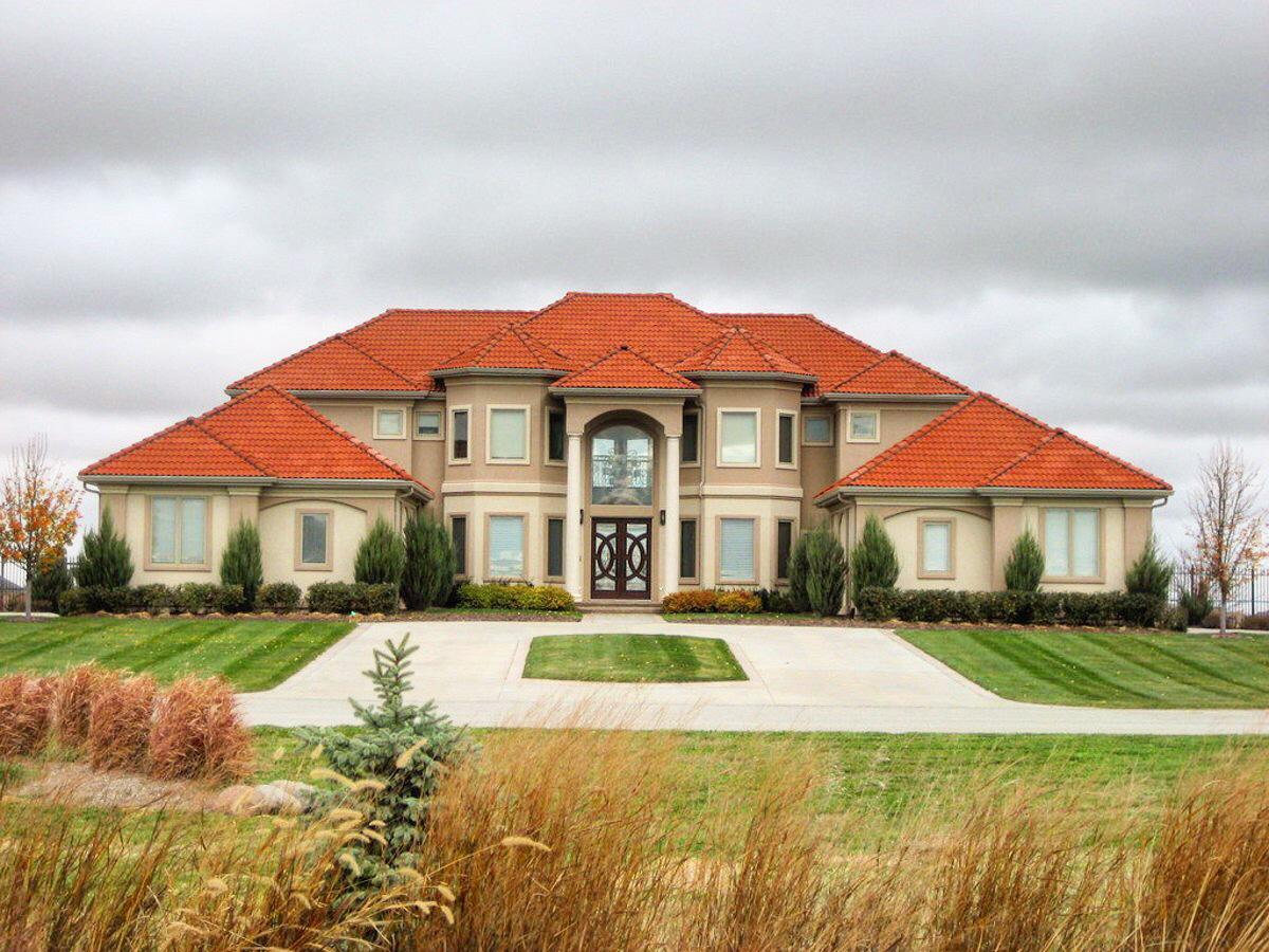 House plan exterior shows a large, two-story home with a red tile roof, central arched entryway, and symmetrical window placement.