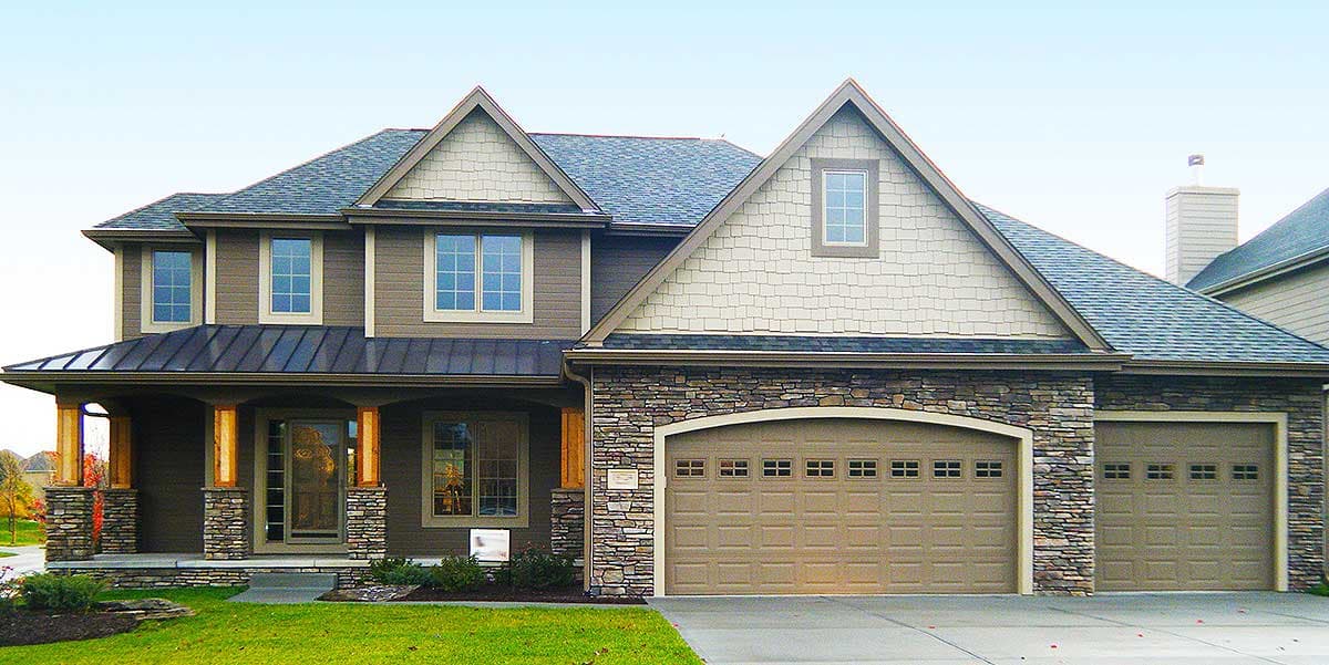 Two-story house plan exterior with stone accents, multiple gables, covered porch with stone pillars, and a three-car garage.