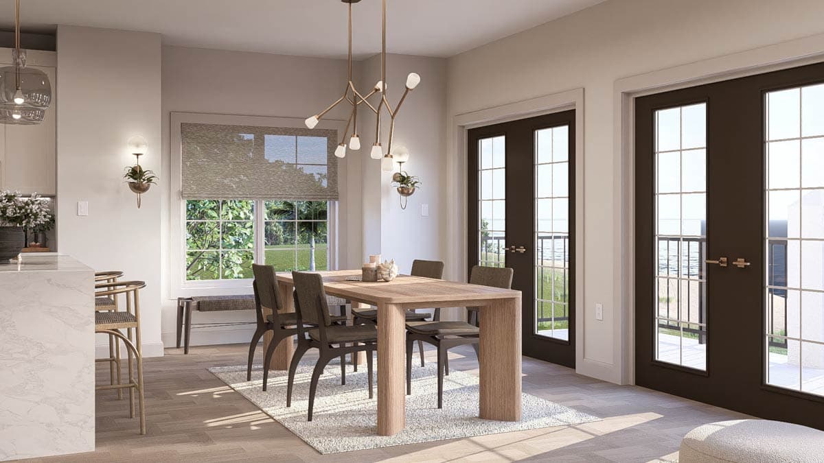 Dining area with a wooden table and chairs, adjacent to a kitchen island, window, and French doors.
