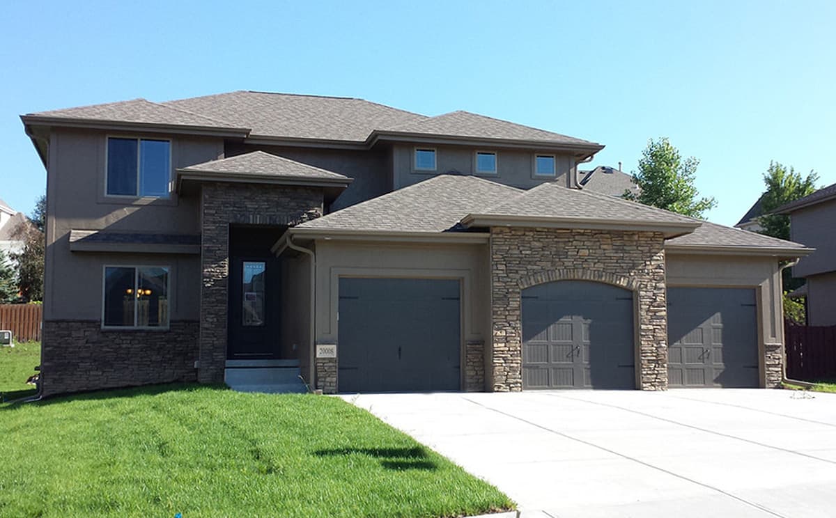 House plan exterior: Two-story home with stucco siding, stone accents, a covered entryway, and a three-car garage.