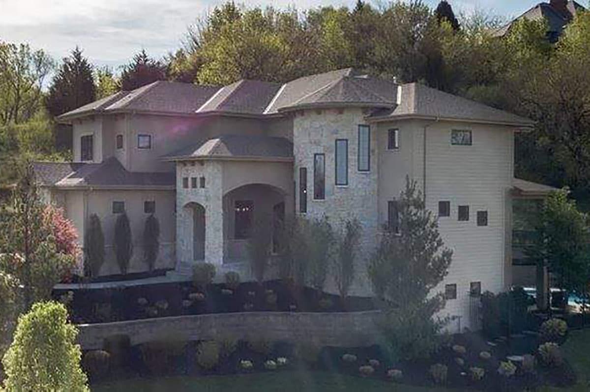 House plan exterior of a two-story modern home with a stone turret, arched entryway, and varied rooflines.