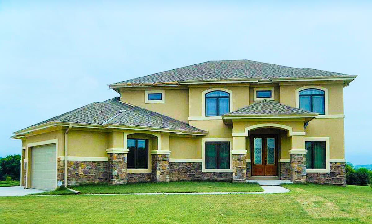 Two-story house plan exterior with stucco finish, stone accents, prominent entryway, arched windows, and attached garage.