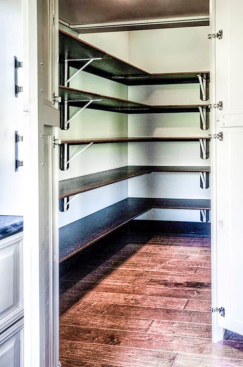 Pantry with corner shelving and dark wood plank flooring.