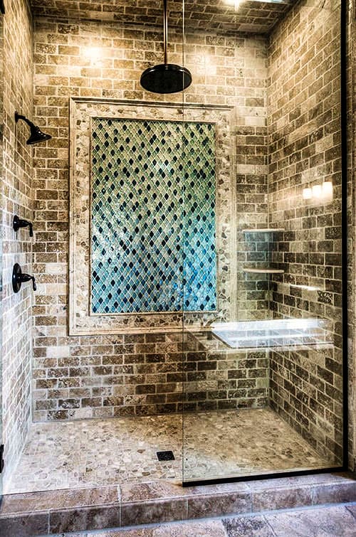 Modern bathroom interior view of a glass-enclosed shower with brick tile walls, a mosaic tile accent, and a built-in bench.