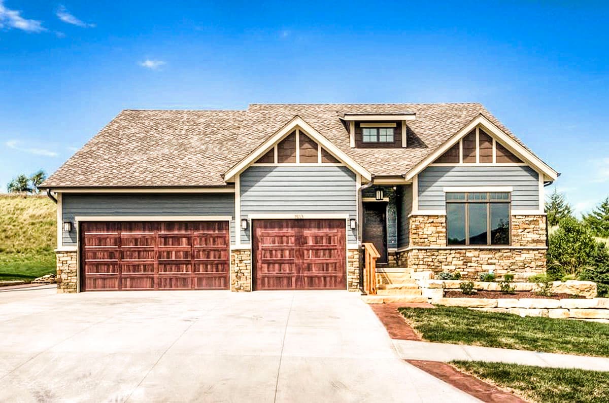 House plan exterior: Traditional style, 1.5 stories, with a stone base, horizontal siding, multiple gables, and a 3-car garage.