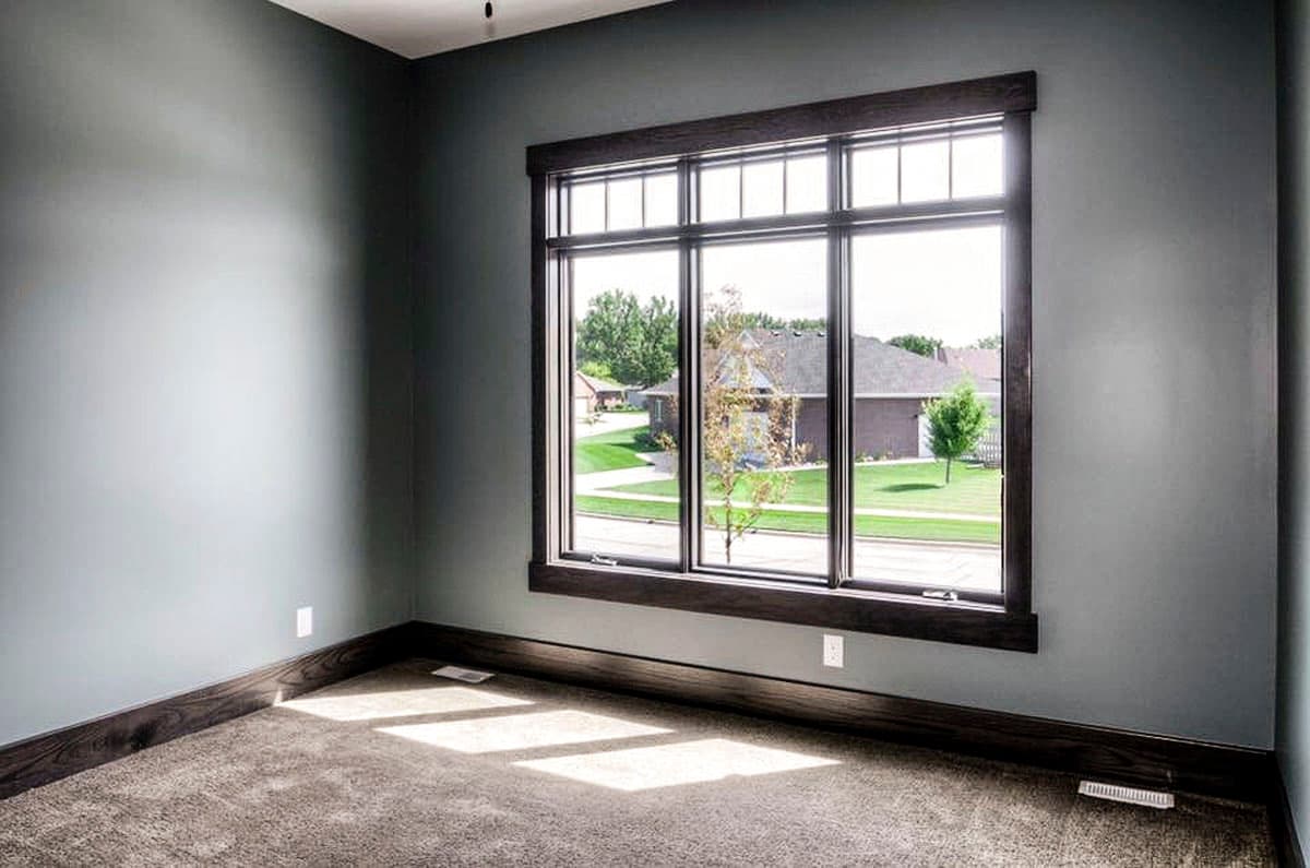 Interior view of a room with a large multi-pane window, dark wood trim, and carpeted floor.