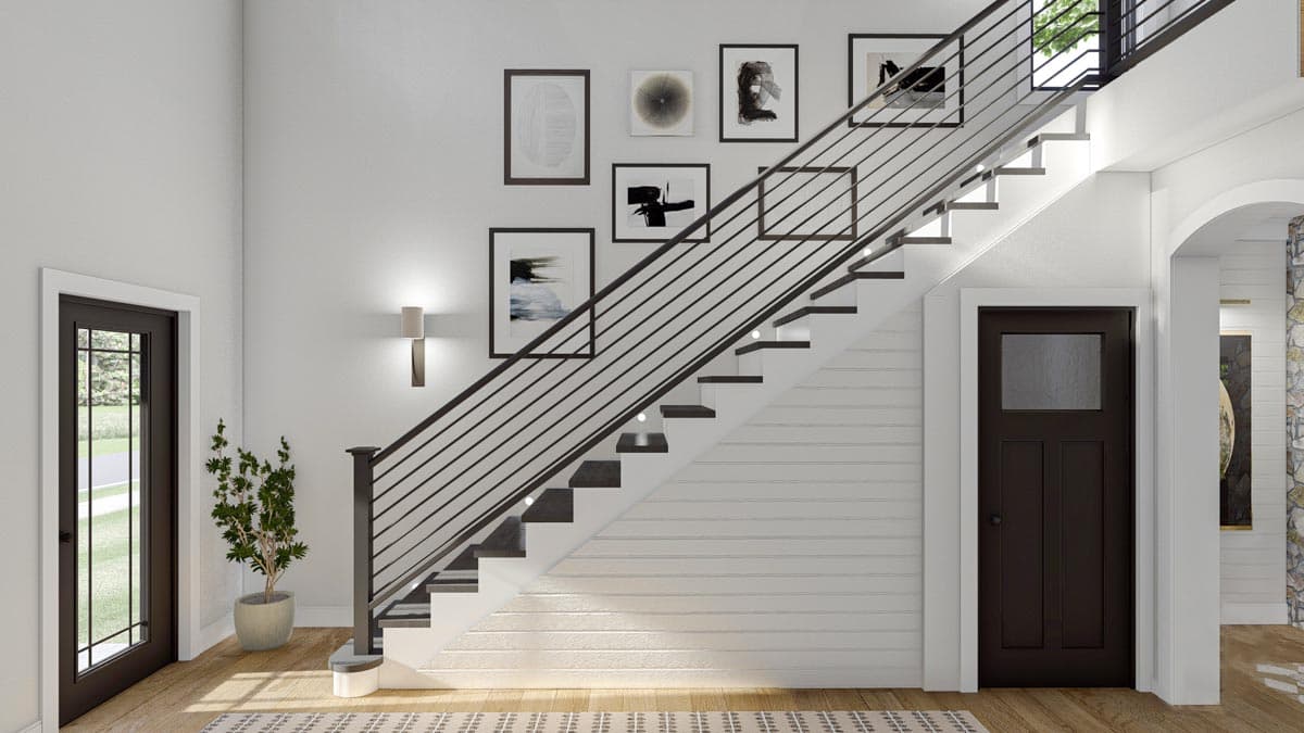 Interior view of a modern staircase with open risers, black metal railings, wall art, and two dark wood doors.