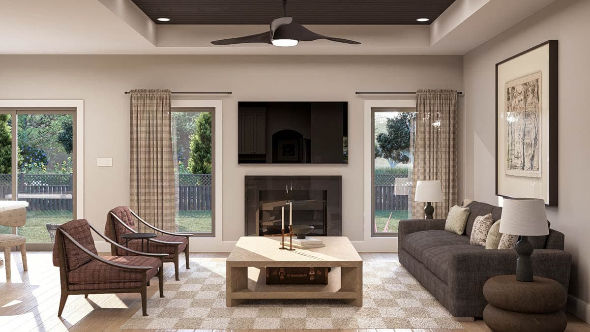 Living room with fireplace, television, two chairs, sofa, and coffered ceiling with fan.