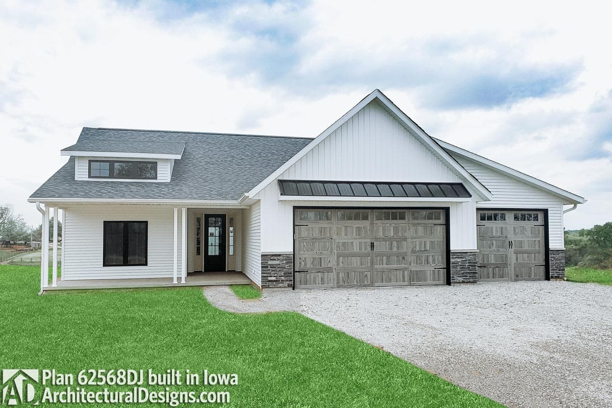 House plan exterior: Modern Farmhouse style, one-story with a prominent dormer, covered front porch, and a three-car garage with dark wood doors.