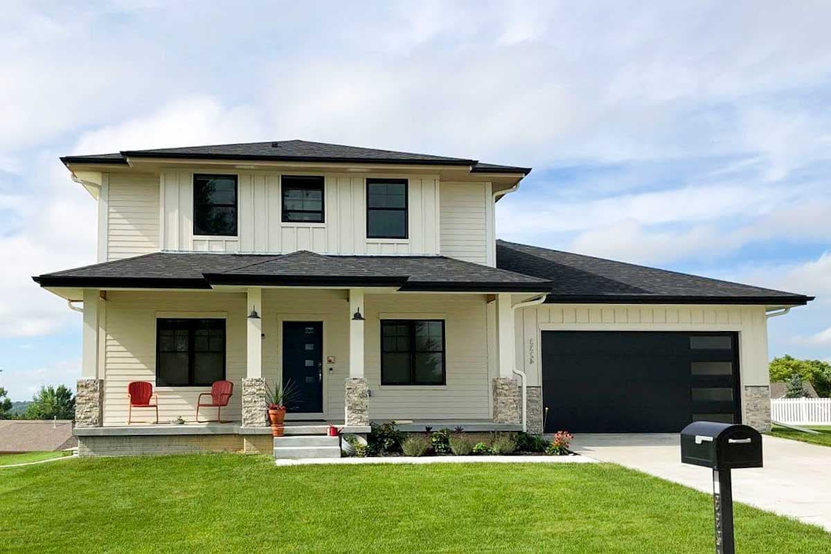 House plan exterior. Two-story Modern Farmhouse with a covered porch, board and batten siding, and a garage with a black door.