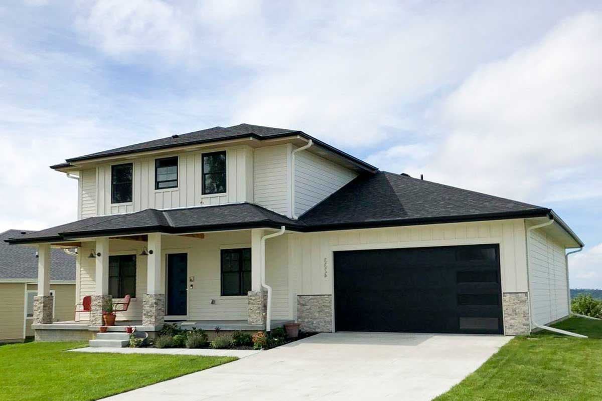 House plan exterior: Two-story home with a covered front porch, stone accents, and a modern black garage door with glass panels.