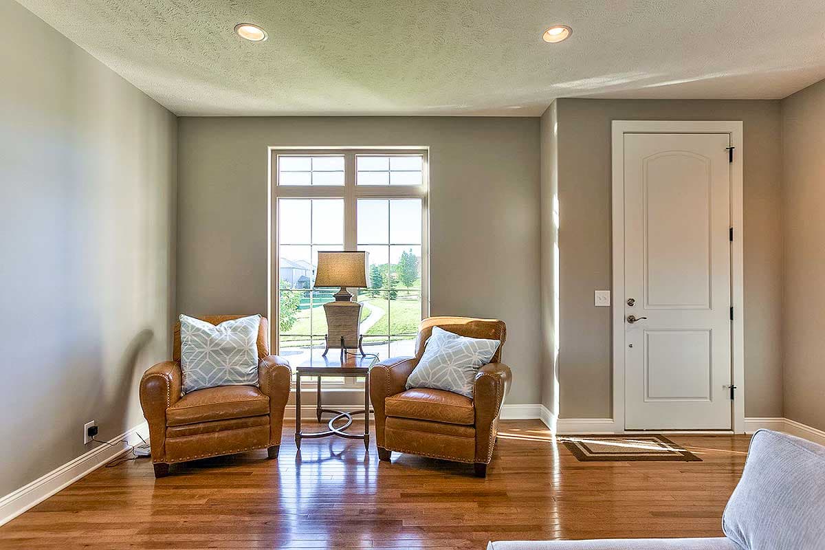 Interior view of a living area with two leather armchairs, a lamp on a side table, and a white paneled door.