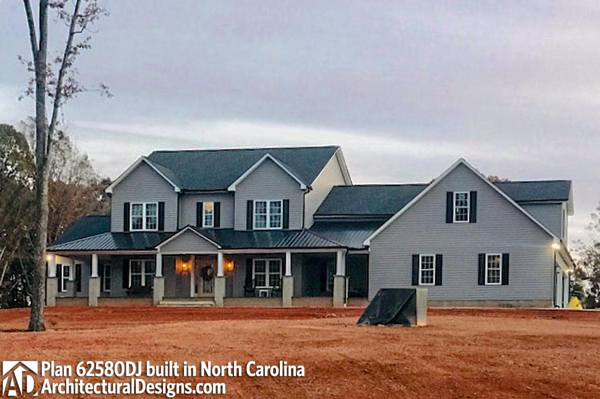 House plan exterior: Two-story Modern Farmhouse with wraparound porch, metal roof sections, and multiple gables.