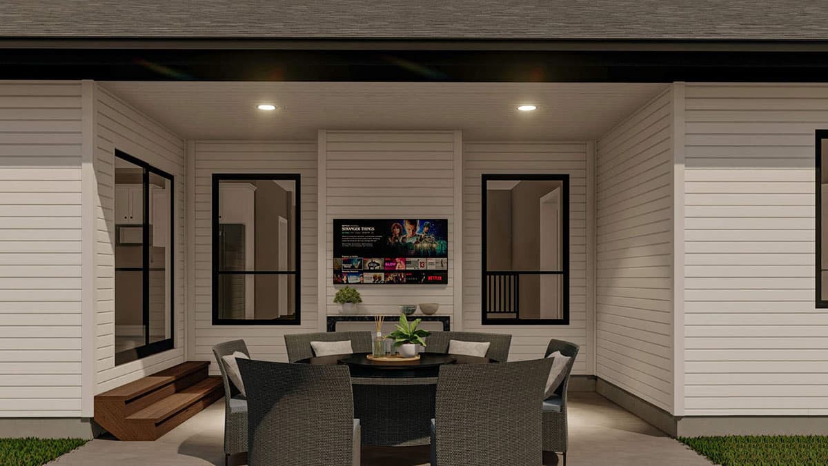 Covered outdoor living space with seating, dining table, and mounted television.