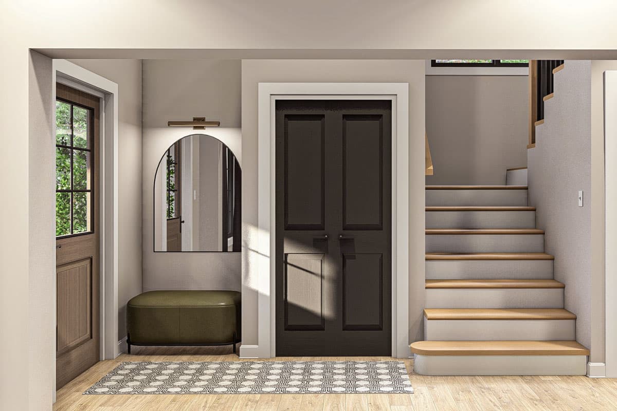 Interior view showing an entryway with a dark paneled door, arched mirror, bench, rug, and staircase.