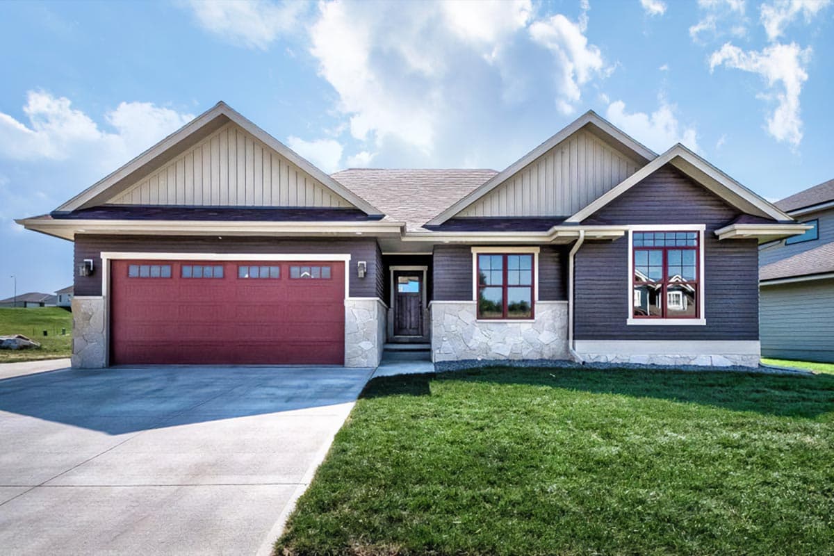 House plan exterior with two gables and a two-car garage. Features include vertical siding and stone accents at the foundation.