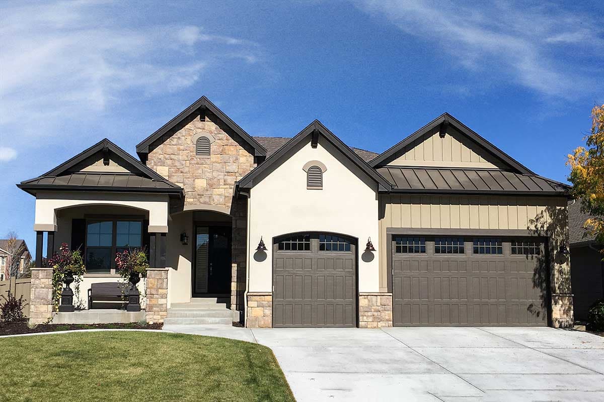 House plan exterior: One-and-a-half-story home with stone accents, a covered porch, and a three-car garage.