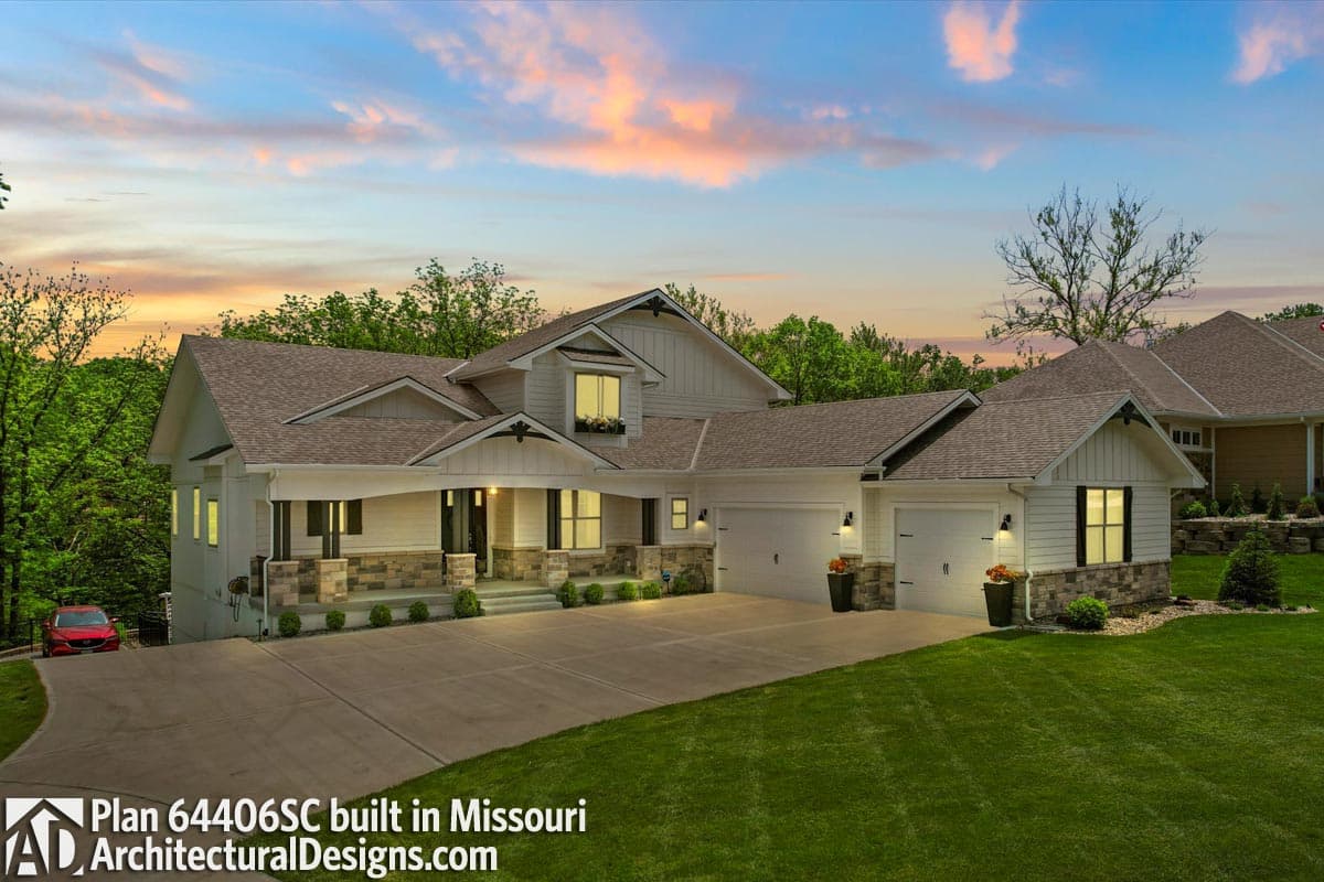 House plan exterior: Modern Farmhouse style, two stories, covered porch with stone columns, multiple gables, and a three-car side-entry garage.