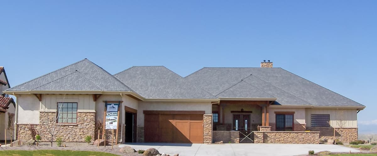 House plan exterior with stone veneer, gabled roof, and attached garage. Includes a covered porch with exposed beams.