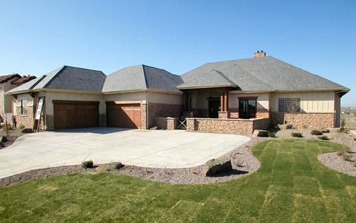 House plan exterior: Single-story residence with a covered entry, three-car garage, stone accents, and varied rooflines.