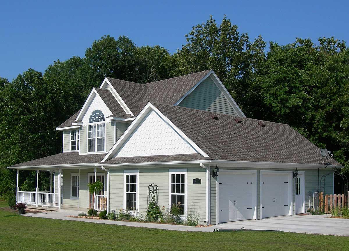 House plan exterior: two-story home with wrap-around porch, arched window, decorative gable, and a three-car attached garage.