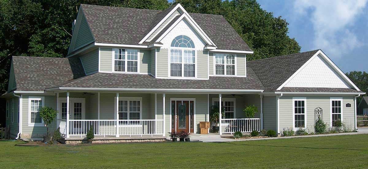 House plan exterior: Two-story home with wraparound porch, multiple gables, and arched dormer window.