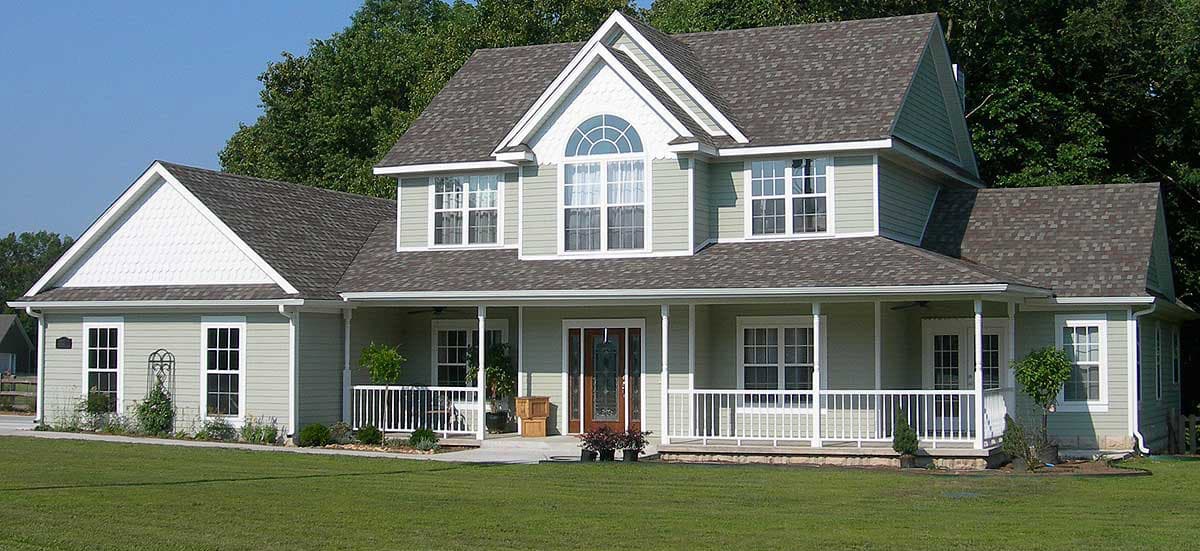 House plan exterior: Two-story home with wraparound porch, multiple gables, dormers, and arched window.
