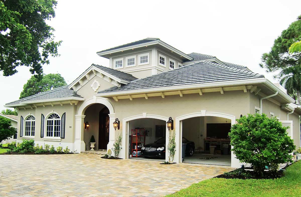 House plan exterior: Two-story Modern Mediterranean style with arched entry, dual garage doors, tile roof, and dormer windows.