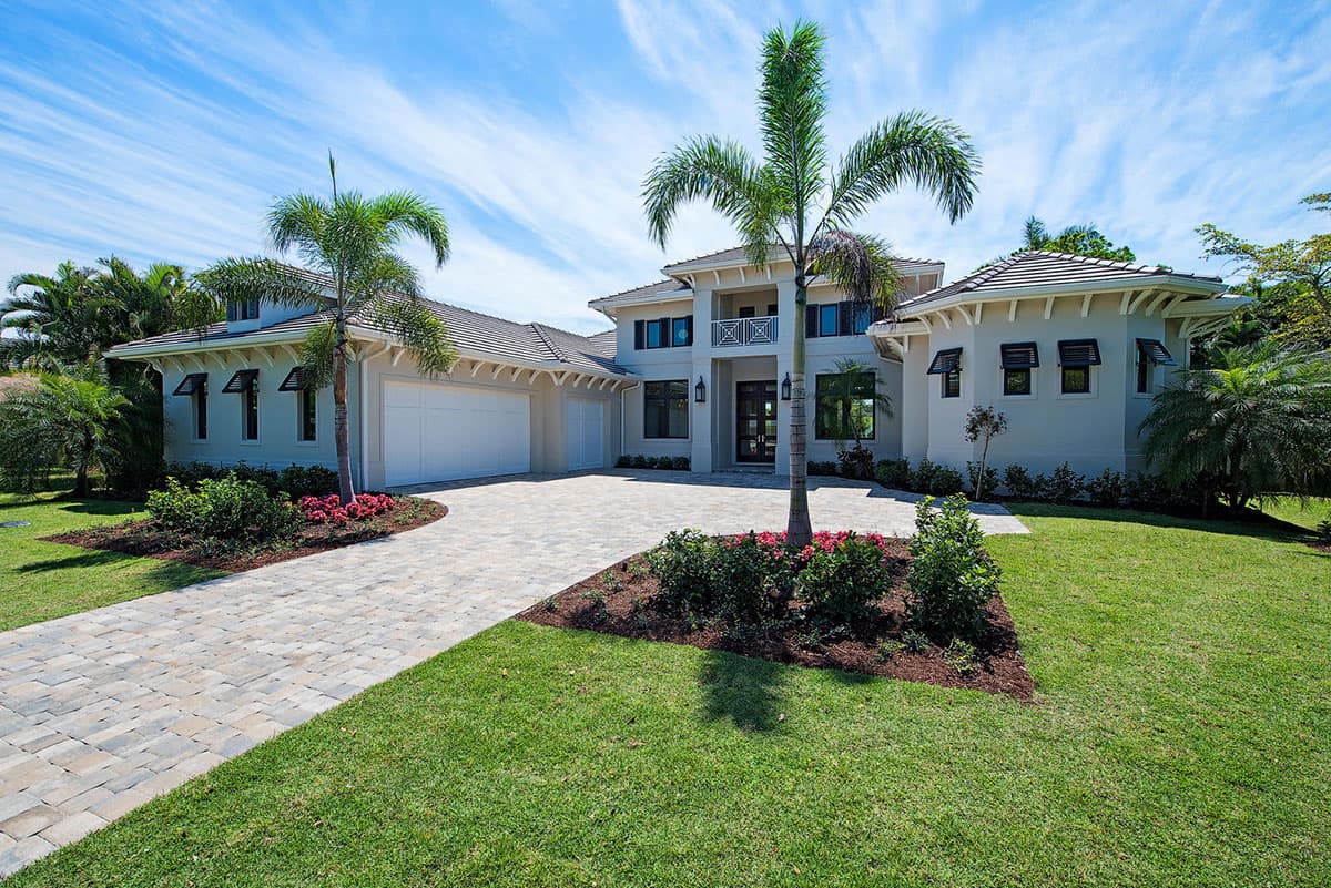 Two-story house plan exterior with a tiled roof, multi-pane windows, a detached three-car garage, and a circular driveway.