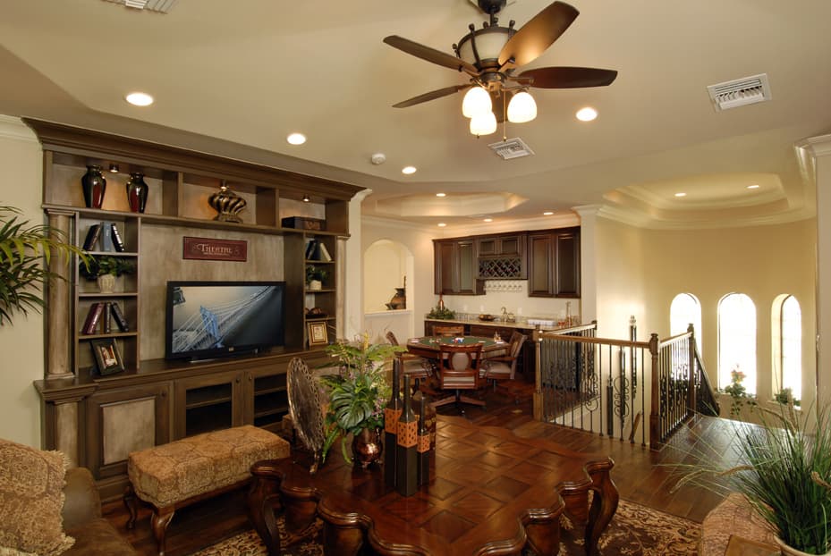 Interior view of a house with entertainment center, dining table, and bar area with arched windows.