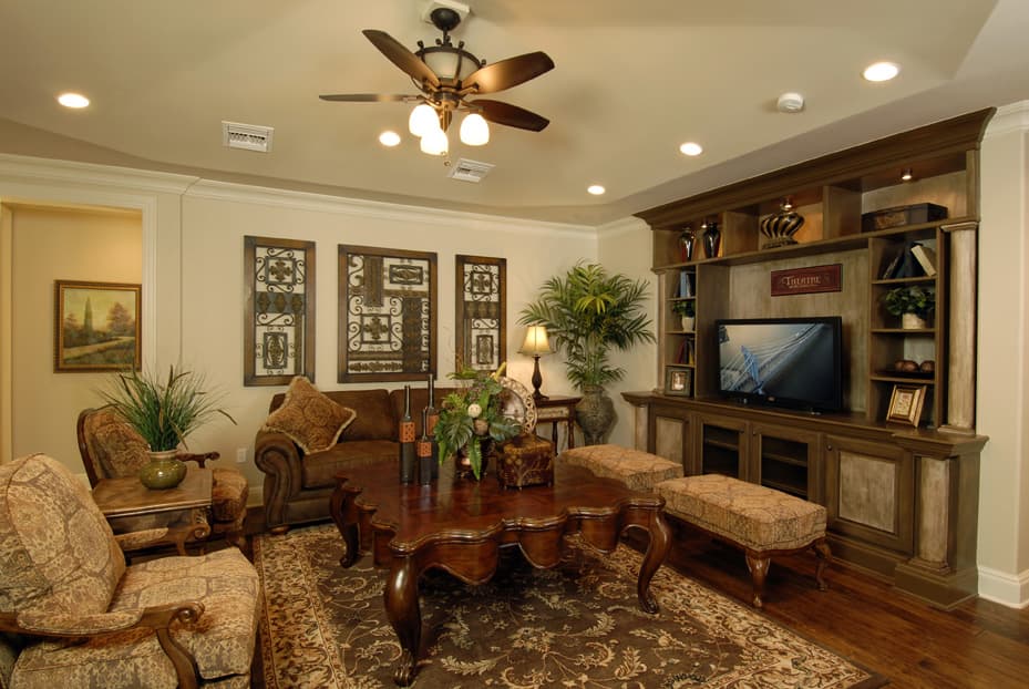 Living room with ornate furnishings, built-in entertainment center, large ornate coffee table, patterned rug, and decorative wall art.